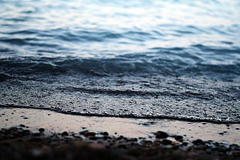 Close-up of gentle ocean waves washing over a pebbly beach