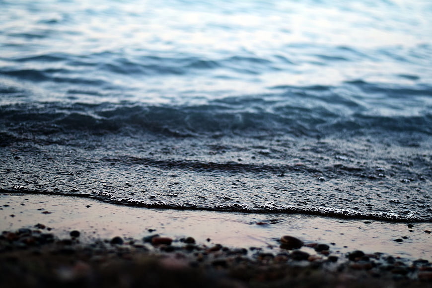 Close-up of gentle ocean waves washing over a pebbly beach