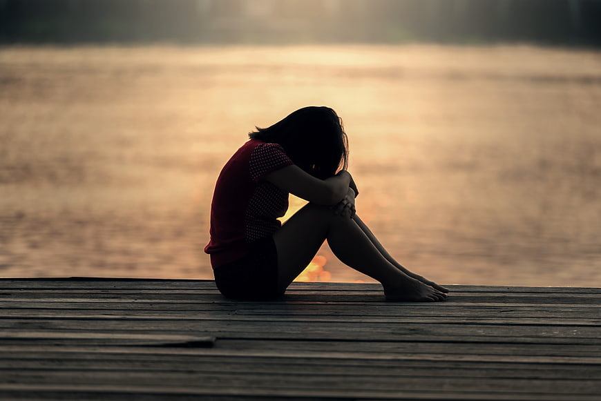 Sad Woman Sitting Alone on Wooden Dock at Sunset