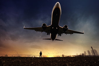 Silhouette of Man Watching Airplane Takeoff at Night