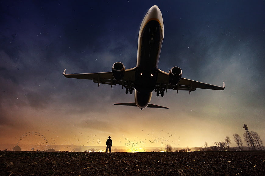 Silhouette of Man Watching Airplane Takeoff at Night