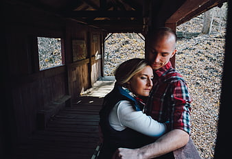 Couple embracing in rustic wooden covered bridge