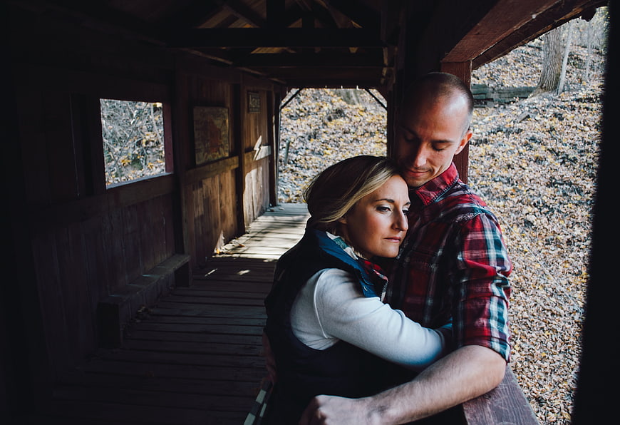 Couple embracing in rustic wooden covered bridge