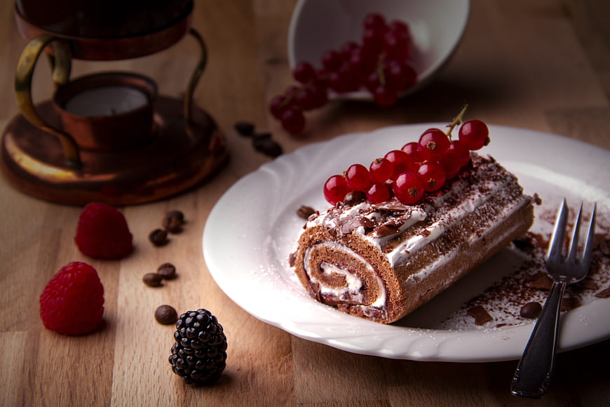 Chocolate Swiss Roll Cake With Red Currants And Berries On Wooden Table