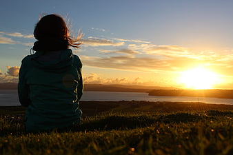 Woman Watching Sunset Over Ocean Landscape