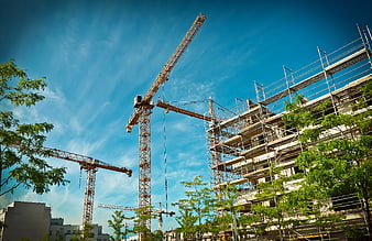Construction site with cranes and scaffolding against blue sky