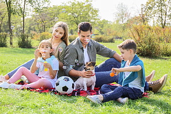 Happy family with dog playing bubbles in park