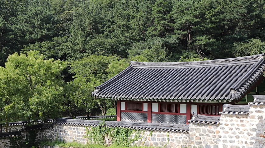 Traditional Korean Hanok House with Stone Wall and Forest