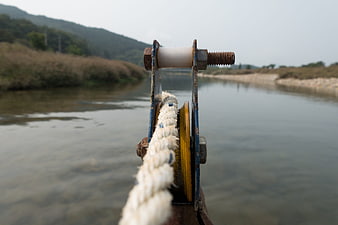 Close-up of boat pulley and rope on a calm river