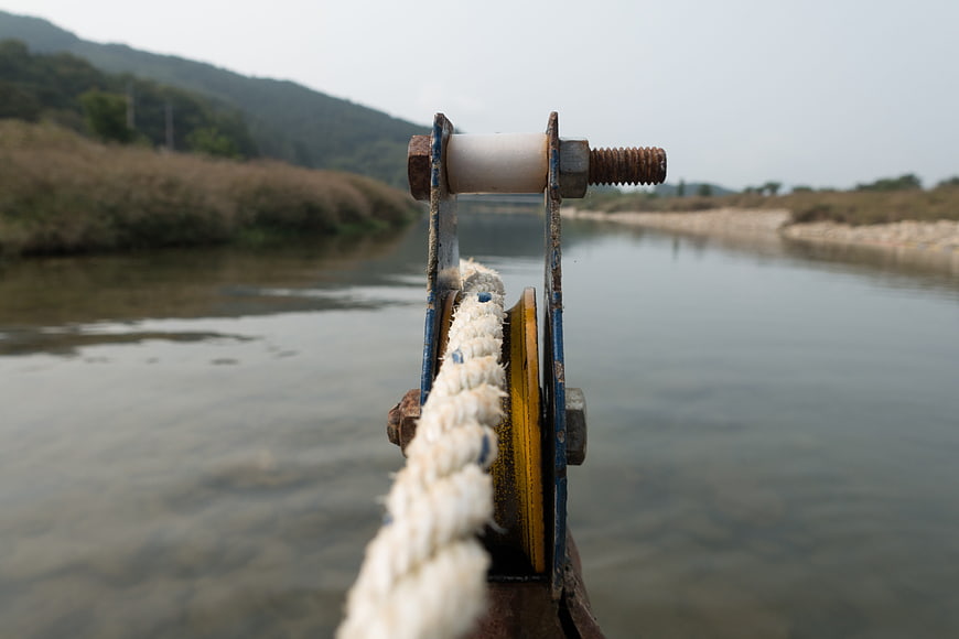 Close-up of boat pulley and rope on a calm river