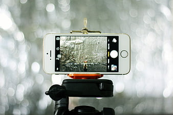 White smartphone on tripod capturing photo with bokeh background