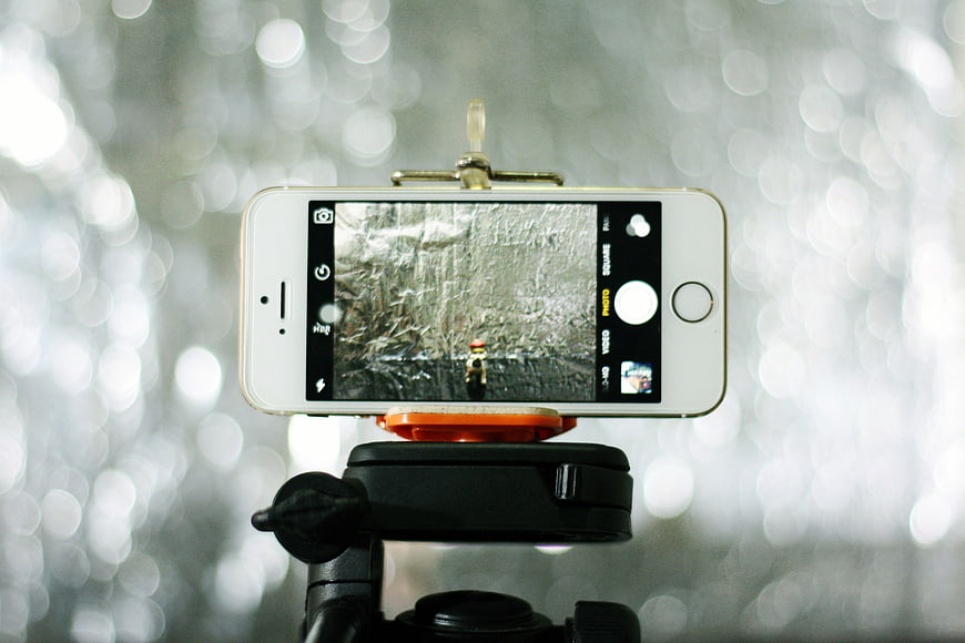 White smartphone on tripod capturing photo with bokeh background