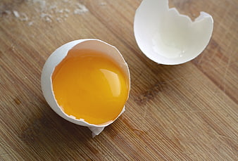 Cracked Egg Yolk in Shell on Wooden Cutting Board