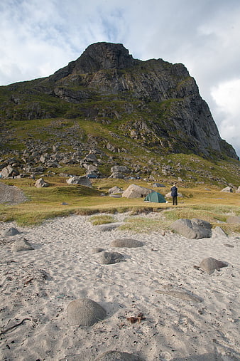 Camping on a sandy beach with a dramatic mountain backdrop in Lofoten, Norway