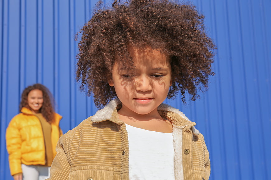 Young Girl with Leaf Shadows on Face Against Blue Wall