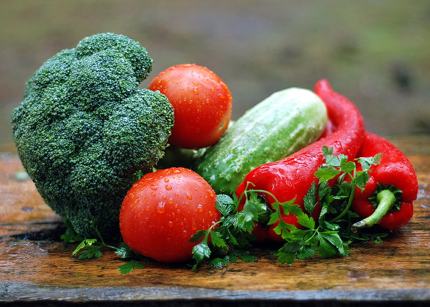 Fresh raw vegetables with water droplets on wooden board