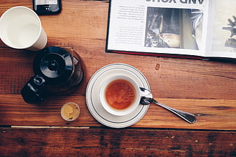 Flat lay of tea cup, teapot, and magazine on rustic wooden table