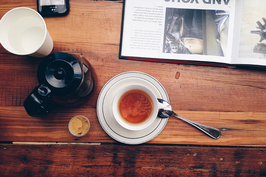 Flat lay of tea cup, teapot, and magazine on rustic wooden table