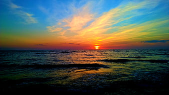 Vibrant Sunset Over Ocean with Colorful Sky and Waves
