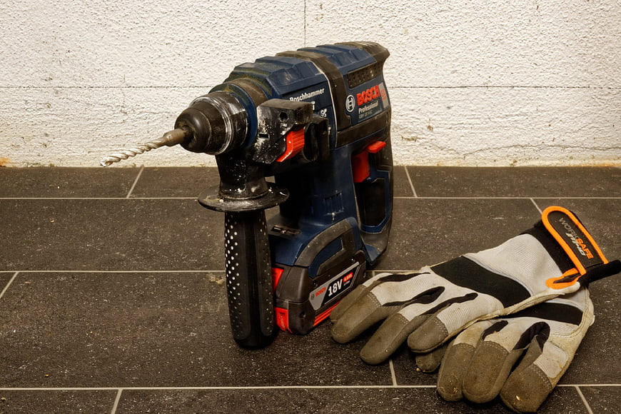 Bosch Cordless Rotary Hammer Drill and Work Gloves on Tile Floor