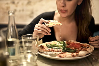 Woman Eating Pizza Slice in Restaurant