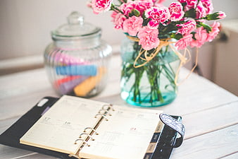 Pink Carnations and Open Planner on White Desk
