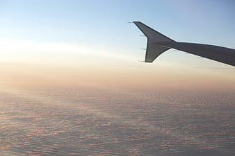 Airplane wing above clouds at sunset