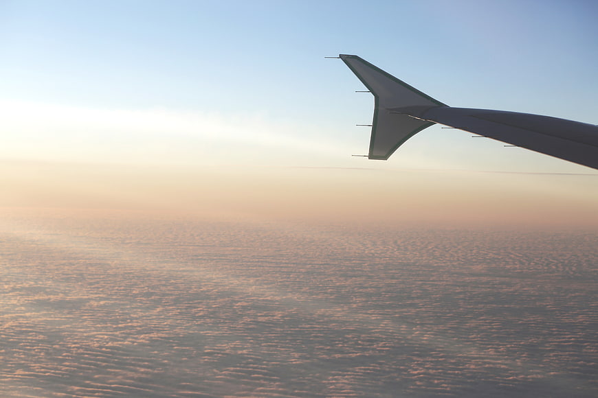 Airplane wing above clouds at sunset
