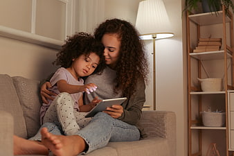 Mother and daughter using tablet on couch at home