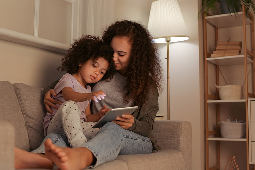 Mother and daughter using tablet on couch at home