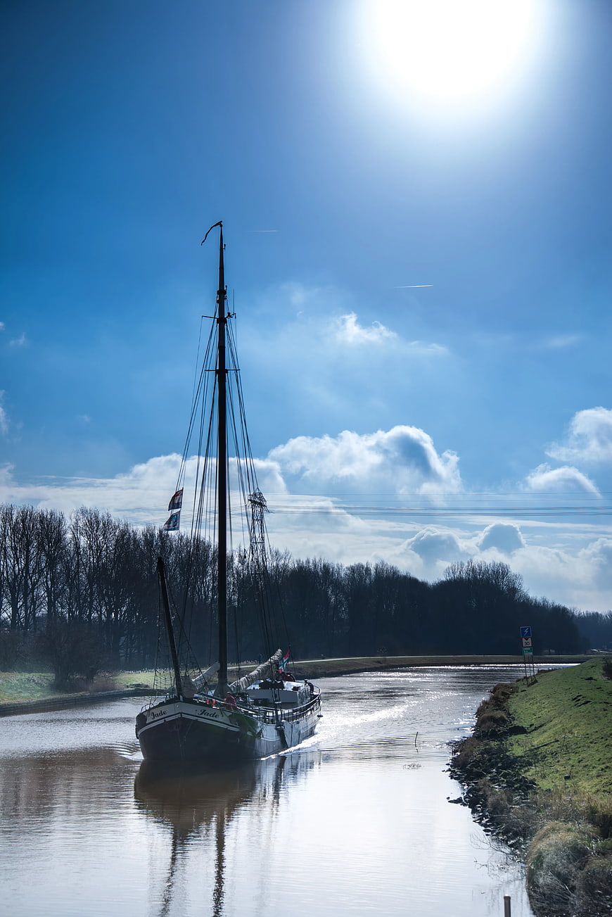Traditional Sailboat Navigating a Sunny River Canal