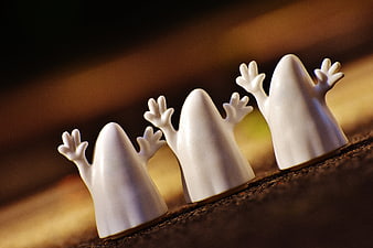 Cute white ghost figurines lined up on a wooden surface