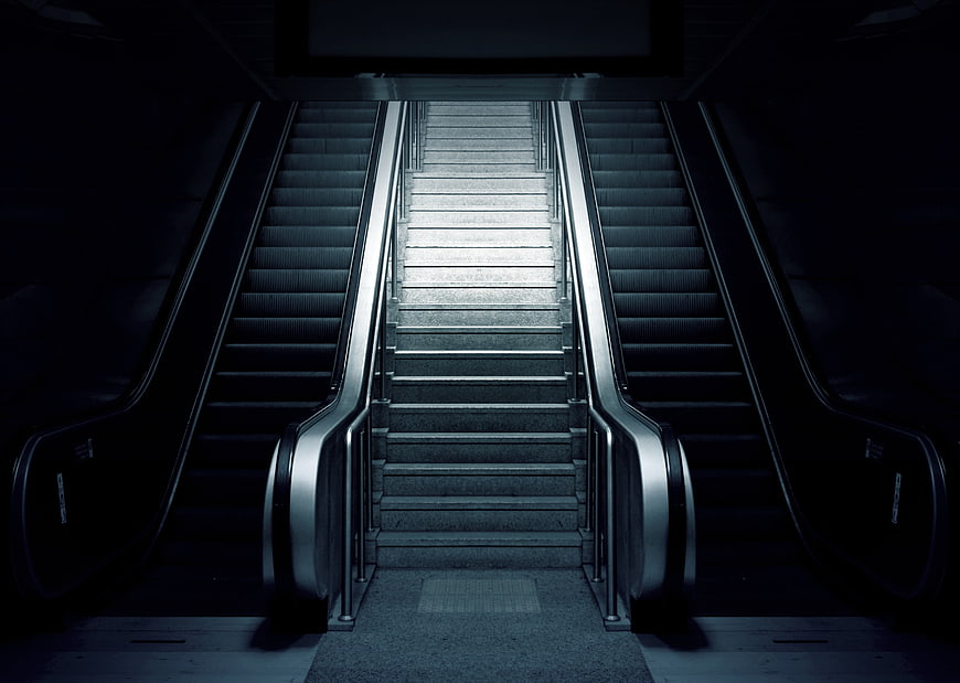 Dark Symmetrical Subway Staircase Between Escalators