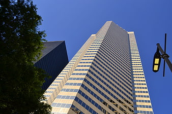 Low angle view of modern glass skyscraper against clear blue sky
