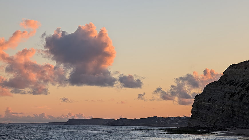 Coastal sunset with dramatic pink clouds and rocky cliffs
