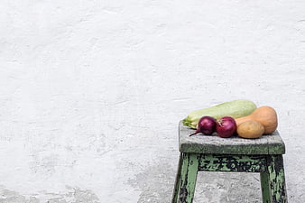 Fresh vegetables on rustic stool against white wall