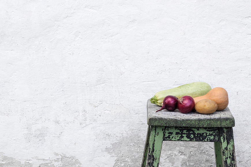Fresh vegetables on rustic stool against white wall