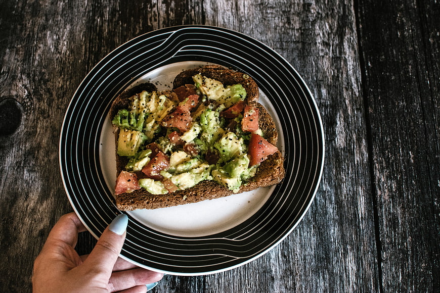 Avocado Toast on Striped Plate Over Dark Wood