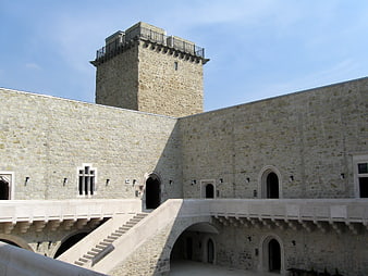 Stone castle courtyard with tower and arched arcade