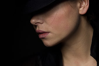 Close-up portrait of woman in black hat with dramatic lighting