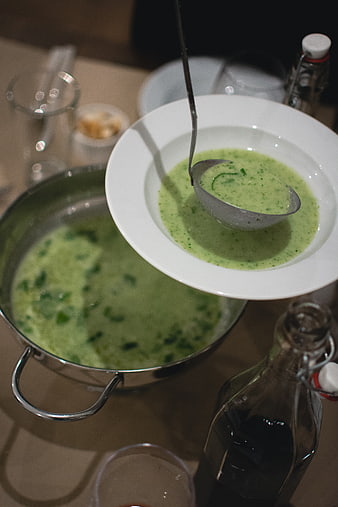 Creamy spinach soup being ladled into a white bowl