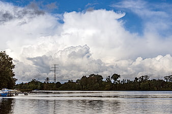 Dramatic Clouds Over River with Trees and Power Lines