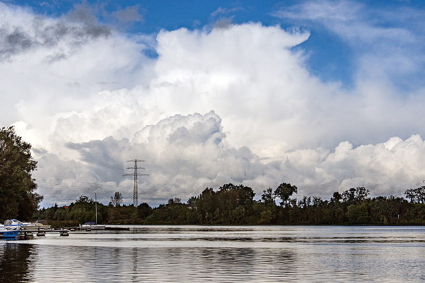 Dramatic Clouds Over River with Trees and Power Lines