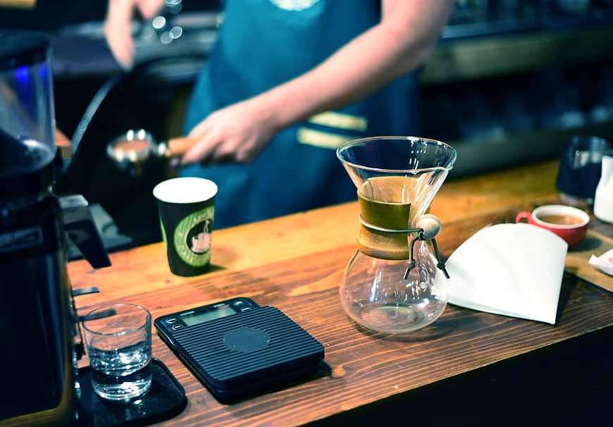 Barista preparing pour-over coffee on wooden counter