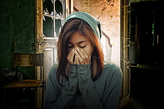 Young woman crying in a dilapidated room with broken window