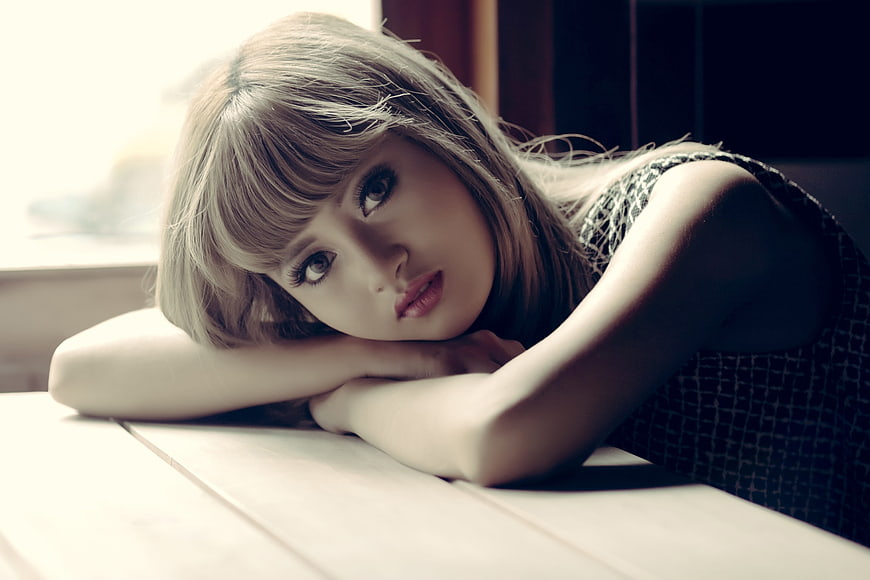 Portrait of a young woman with bangs resting her head on a table