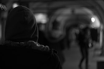 Silhouette of hooded figure in dark tunnel