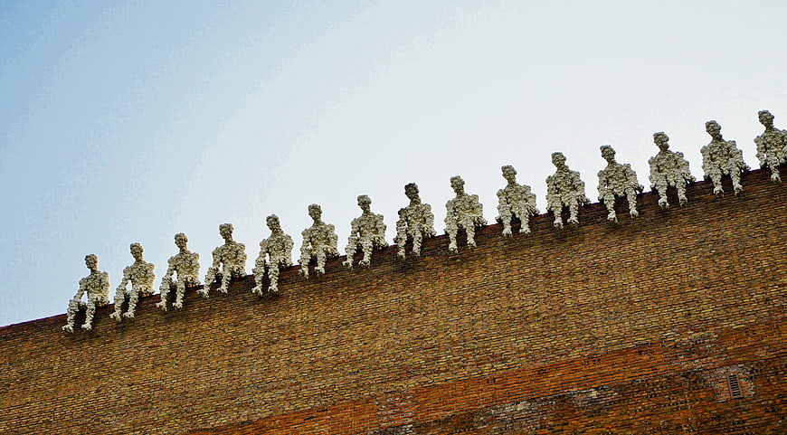 Row of white textured figures sitting on a brick wall