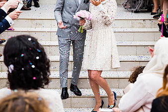 Wedding couple walking down stairs with confetti and guests
