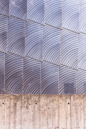 Modern architectural facade with textured metal panels and concrete base